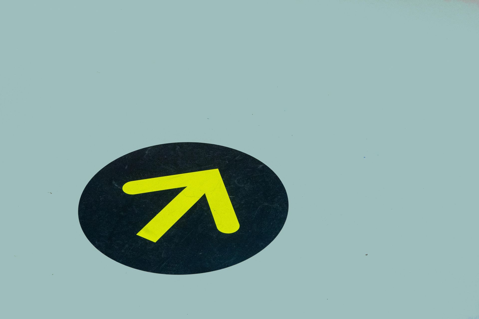 Yellow arrow icon on a black oval background