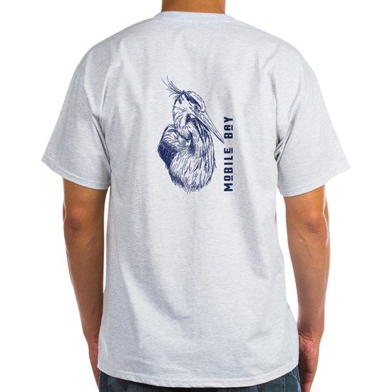 Man wearing a light gray t-shirt with a blue drawing of a heron and the words 