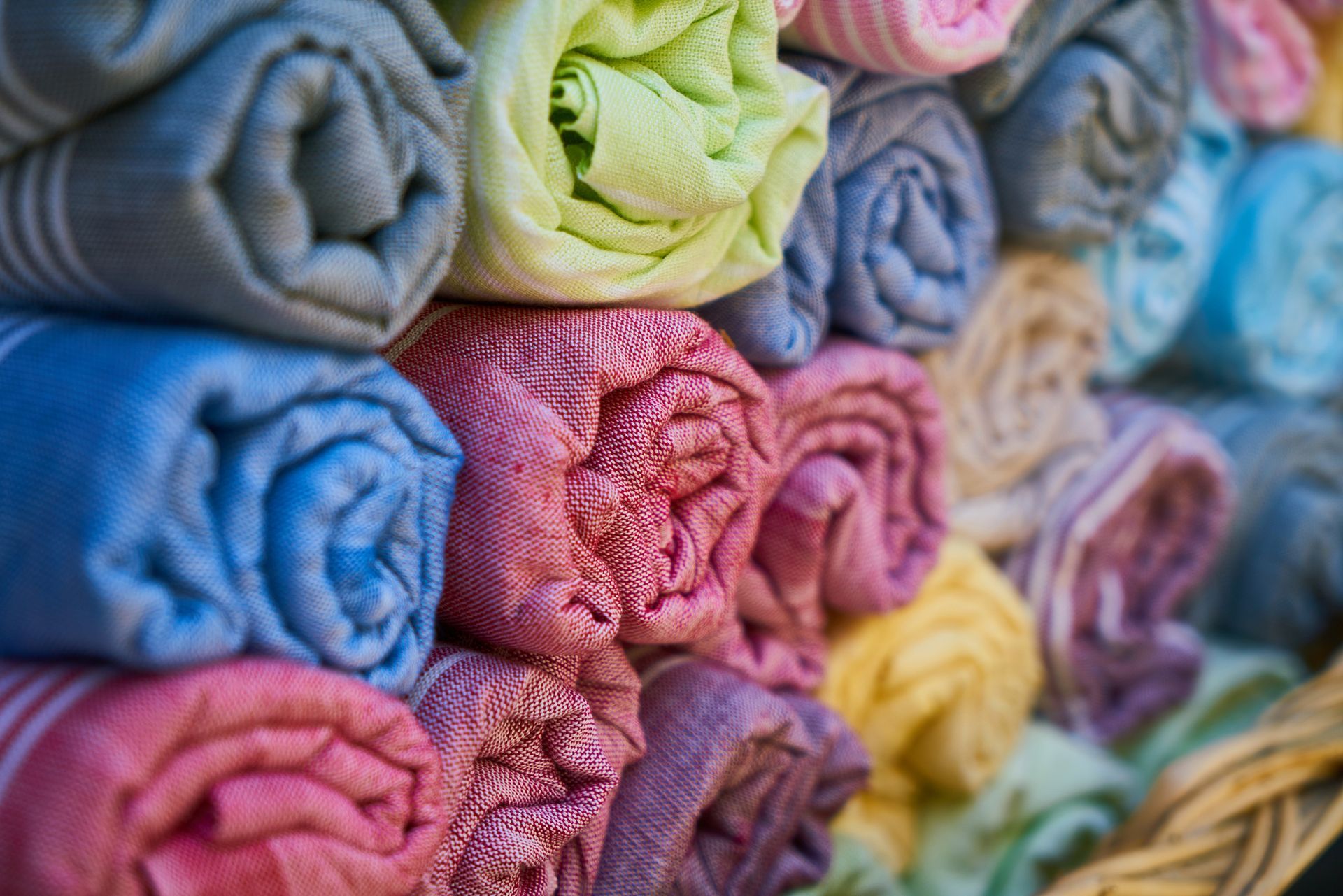 Rolled, colorful towels stacked in a basket; blues, pinks, greens, and yellows are visible.