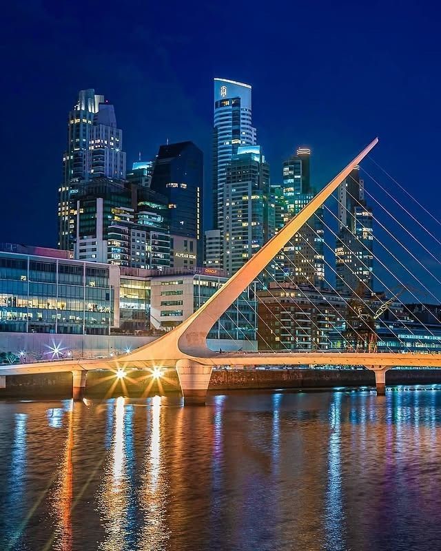 El puente de la Mujer en Buenos Aires por la noche, con un pilón iluminado y cables.