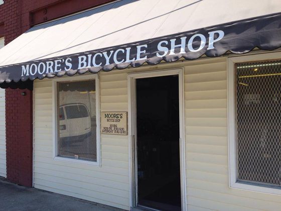 The front of a moore 's bicycle shop with a white awning