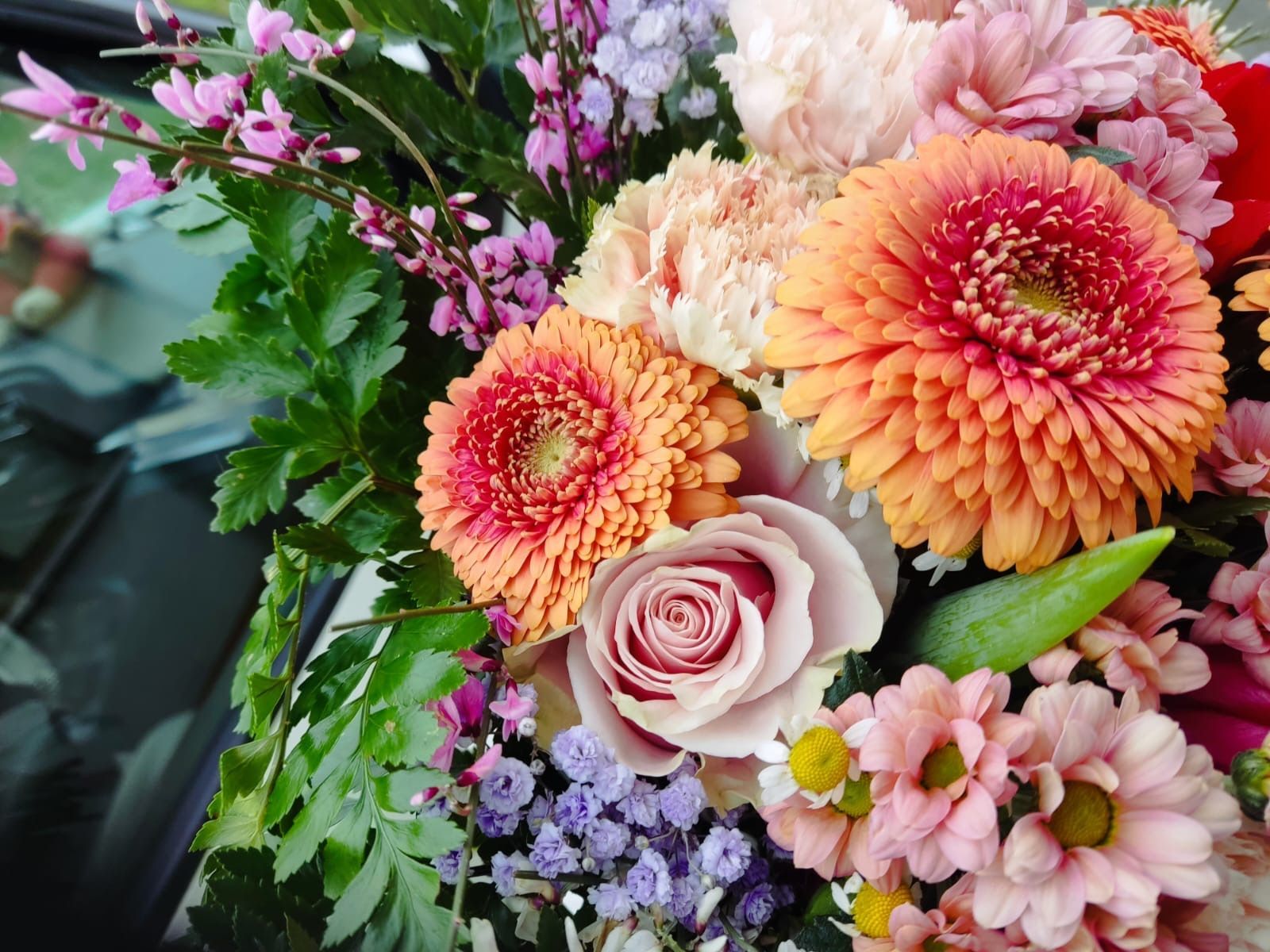 Primo piano di un bouquet di fiori colorati con gerbere arancioni e rose rosa.