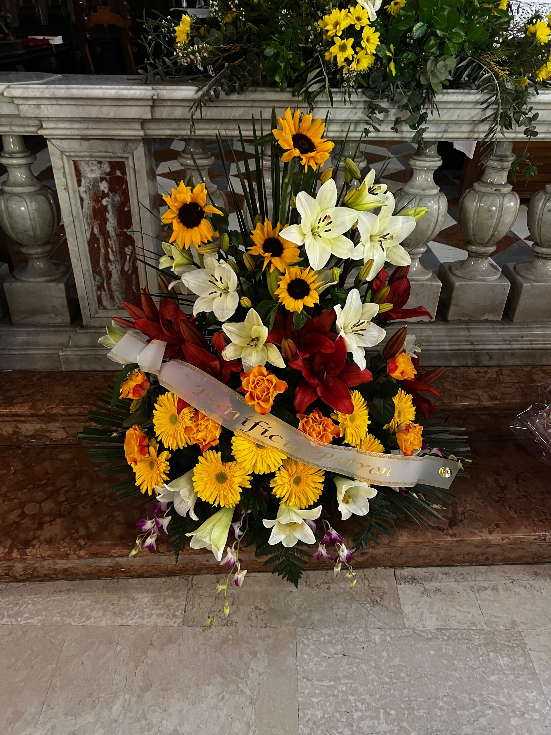 Composizione floreale con girasoli, gigli e calendule, su una superficie in pietra.