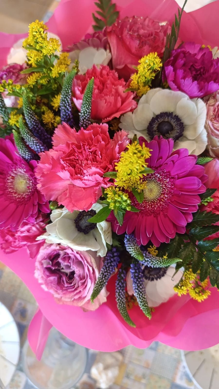 Bouquet luminoso con fiori rosa e bianchi, tra cui garofani, gerbere e anemoni.