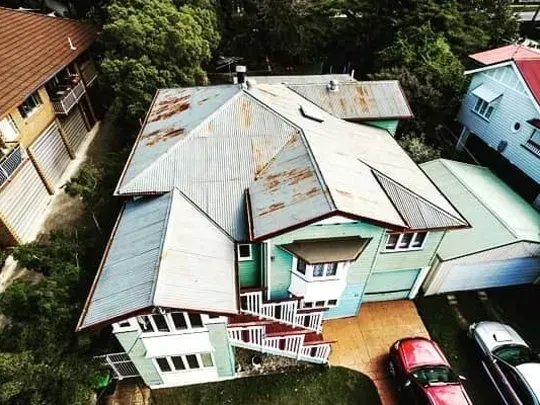 An aerial view of a roof of a house surrounded by trees.