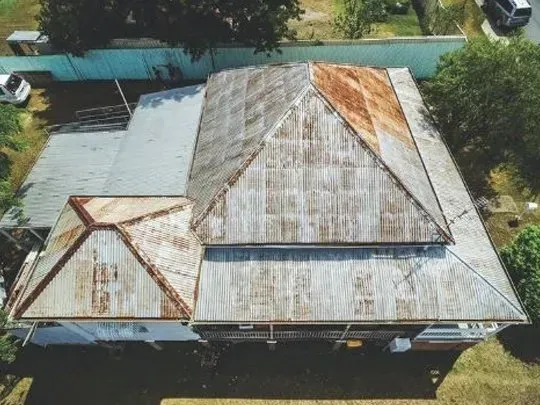 An aerial view of a large house surrounded by trees and grass.