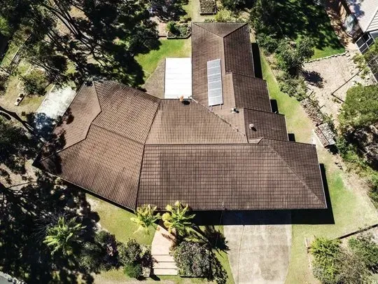 An aerial view of a large house surrounded by trees and grass.