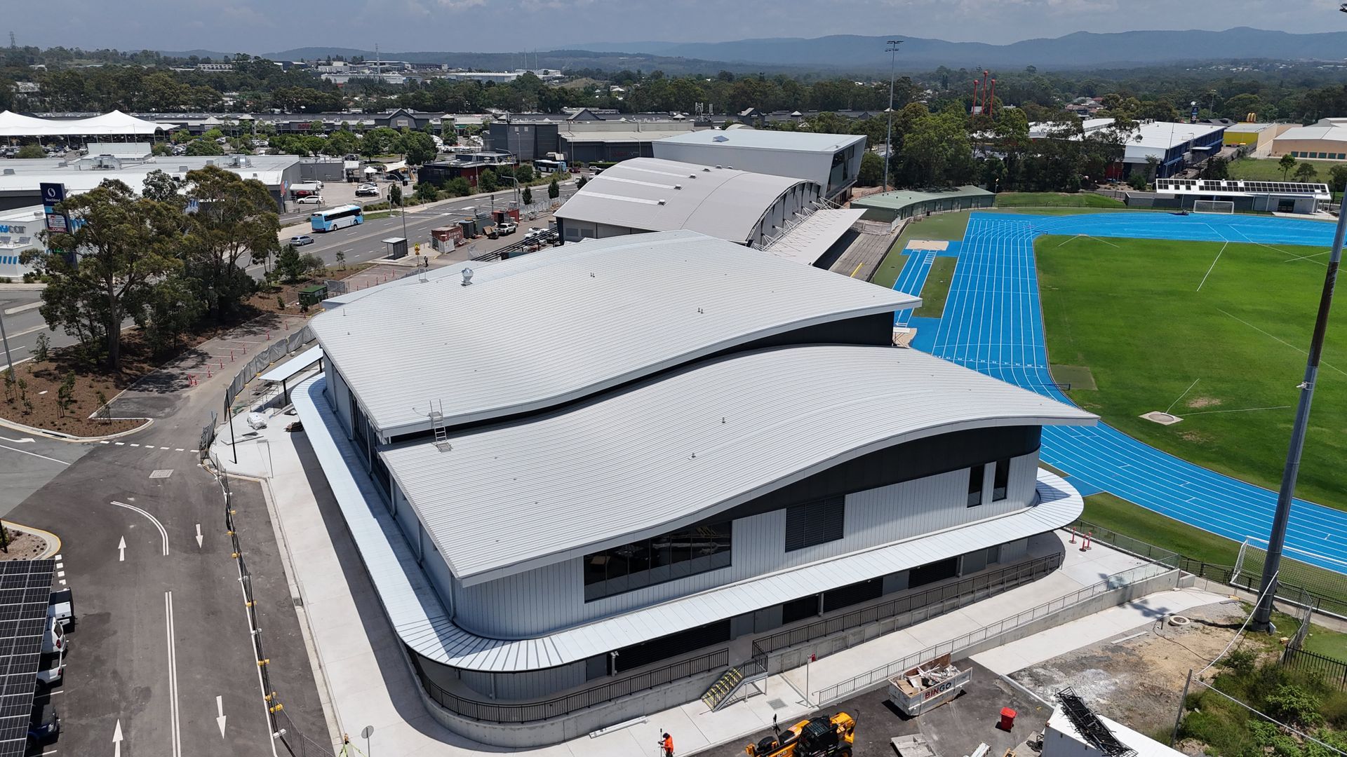 An aerial view of a large building with a blue track in the background.
