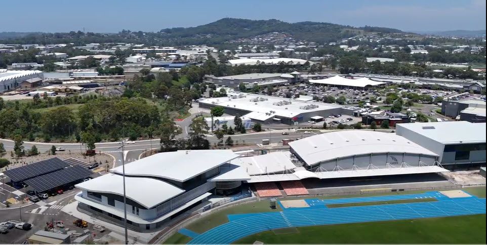 An aerial view of a large building with a blue track in front of it.