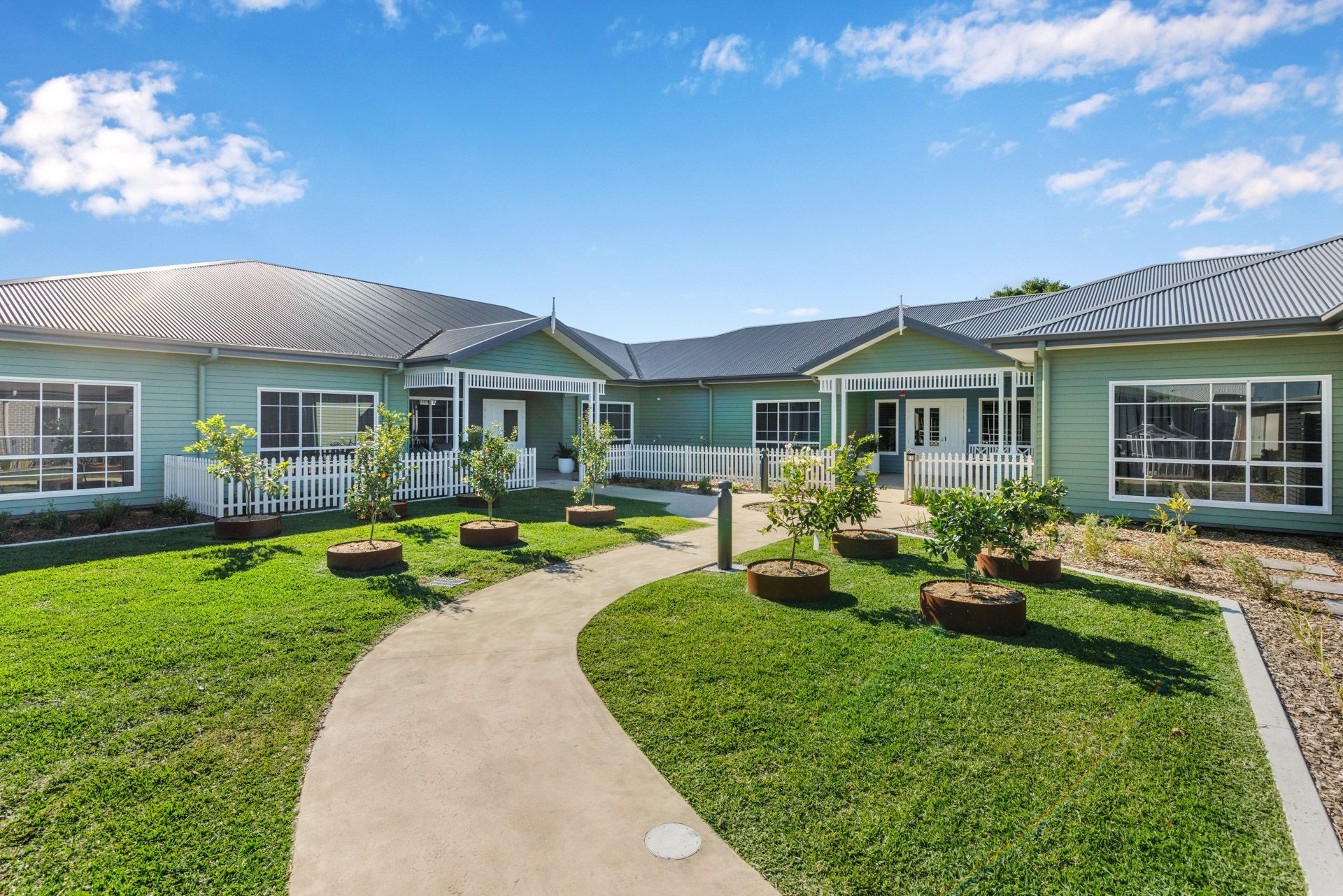 A large green house with a walkway leading to it.