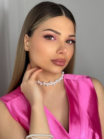 Eine Frau, die ein rosa Oberteil und eine Perlenkette trägt