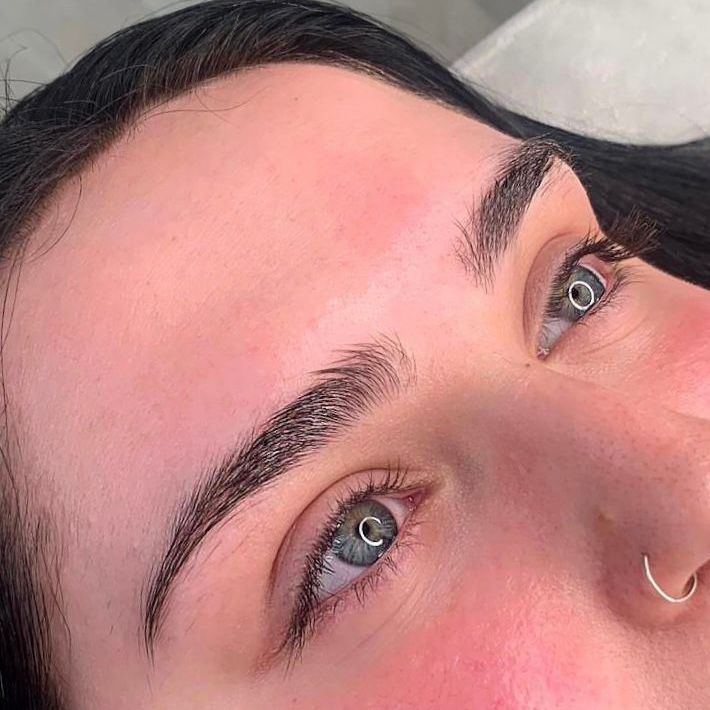 Eine Nahaufnahme des Gesichts einer Frau mit langen Wimpern und einem Nasenring.