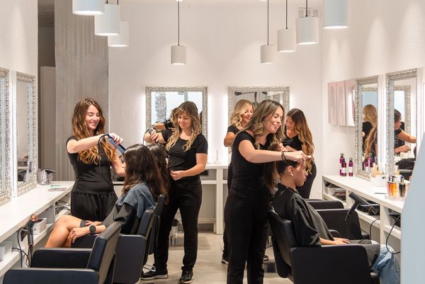 Hairdressers styling clients' hair in a modern salon. Hairdressers styling clients' hair in a modern salon.