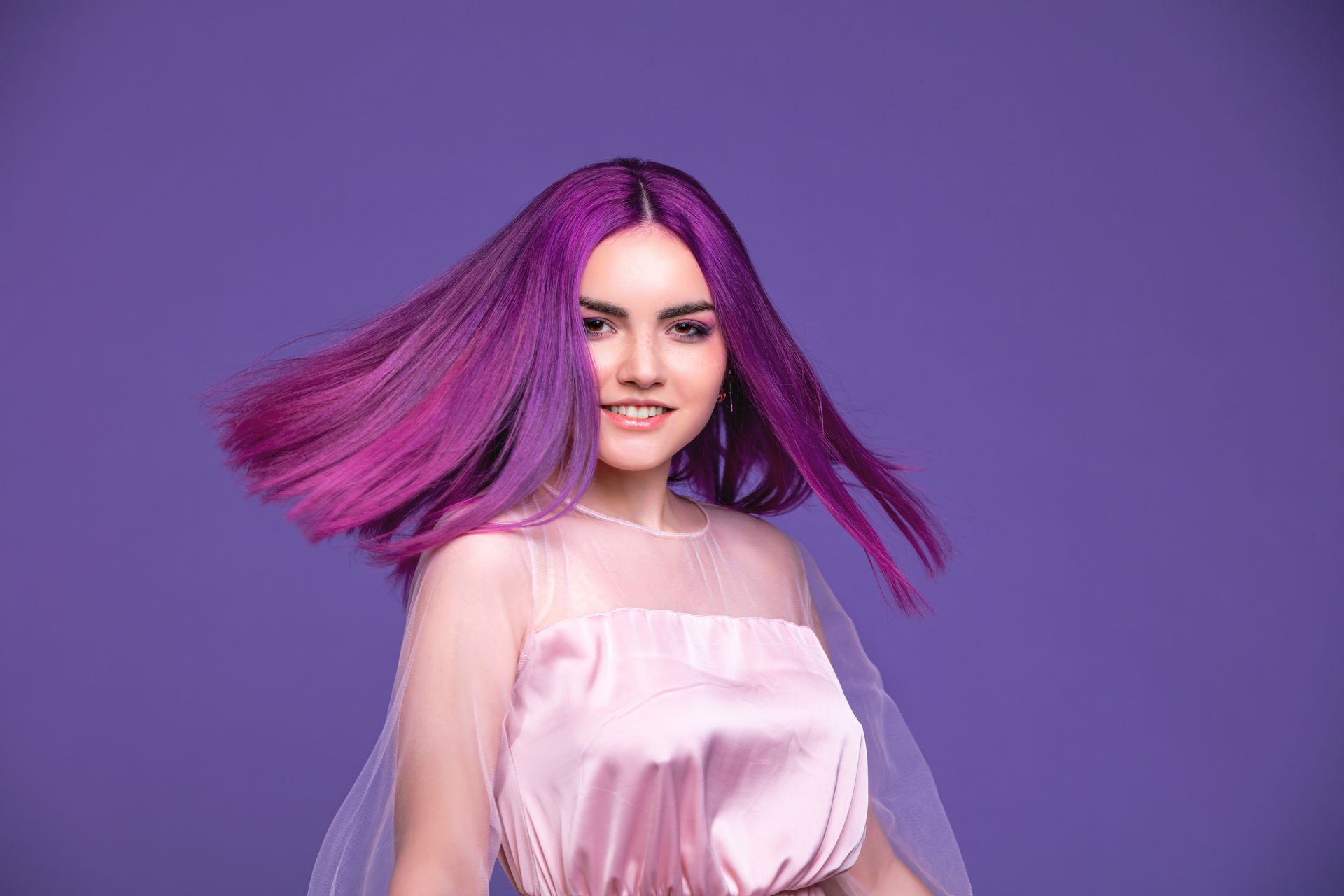 Young stylish model with purple-dyed hair posing on a violet background. Young stylish model with purple-dyed hair posing on a violet background.