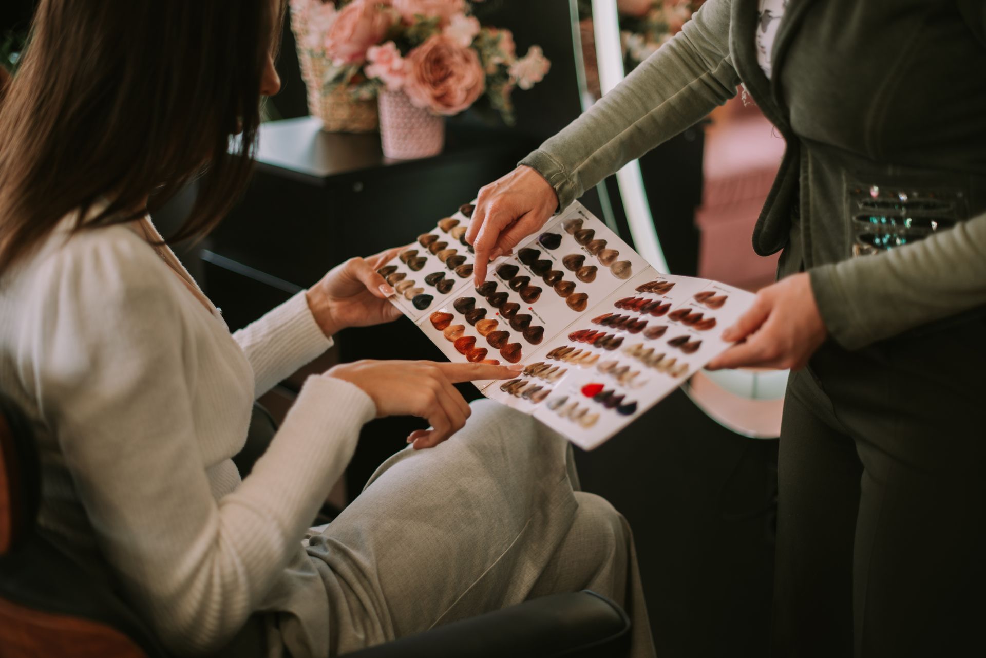 A female client and colorist pointing at the color palette at the hair salon.