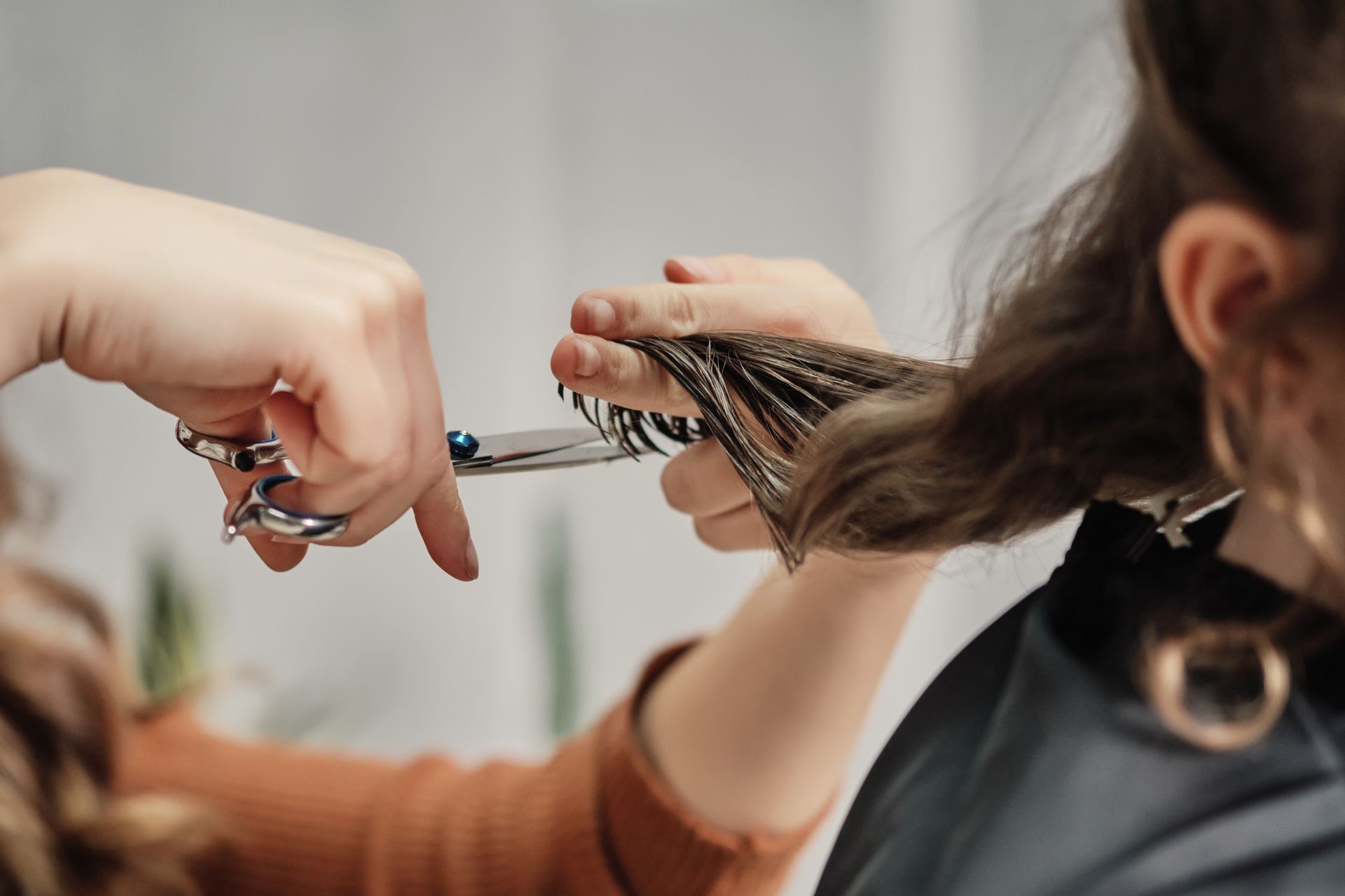 A set of hands with a scissor cutting hair.