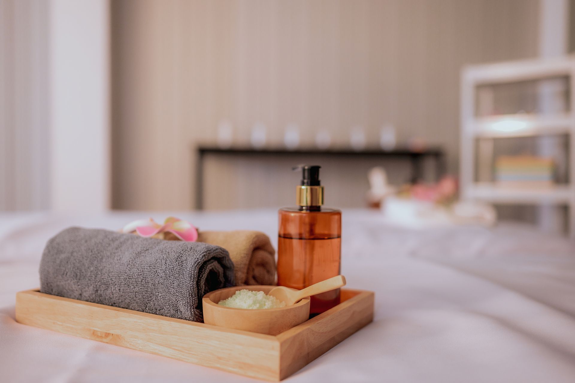Closeup of a wooden tray with oil, towels, and petals for a massage session.