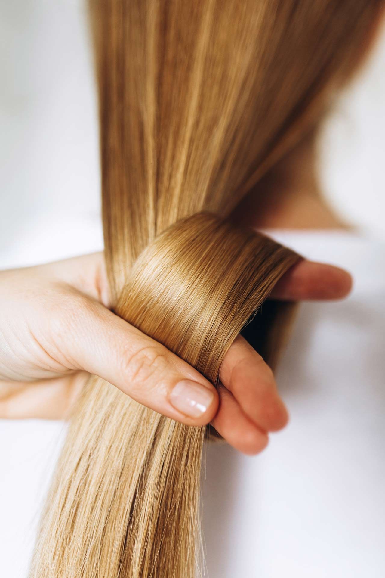 Hand twisting long and blond hair to showcase its beauty and health