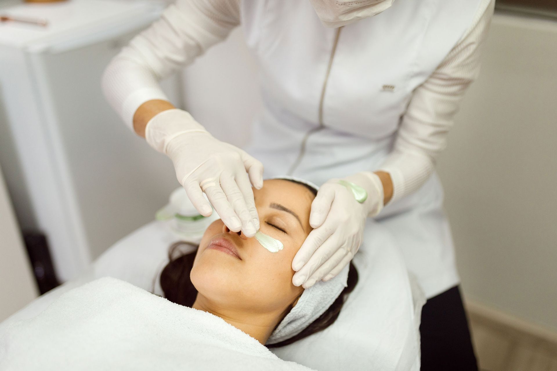 A woman gets an acne facial at a beauty salon as a beautician works on her skin with care. A woman gets an acne facial at a beauty salon as a beautician works on her skin with care.