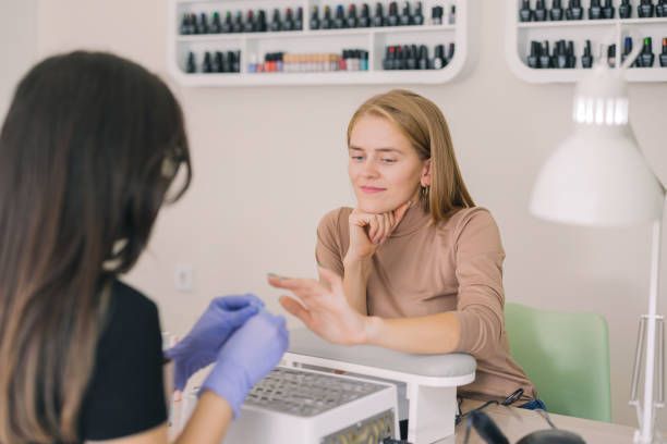 Picture of a client looking at her nails in a happy way for the good job done by the manicurist.