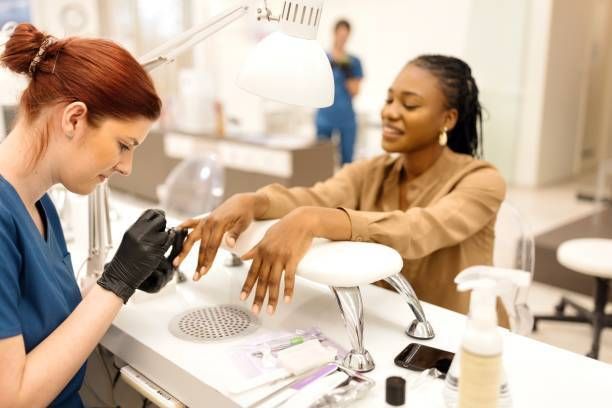 Nail salon technician applying polish to client's nails in modern, clean beauty studio.
