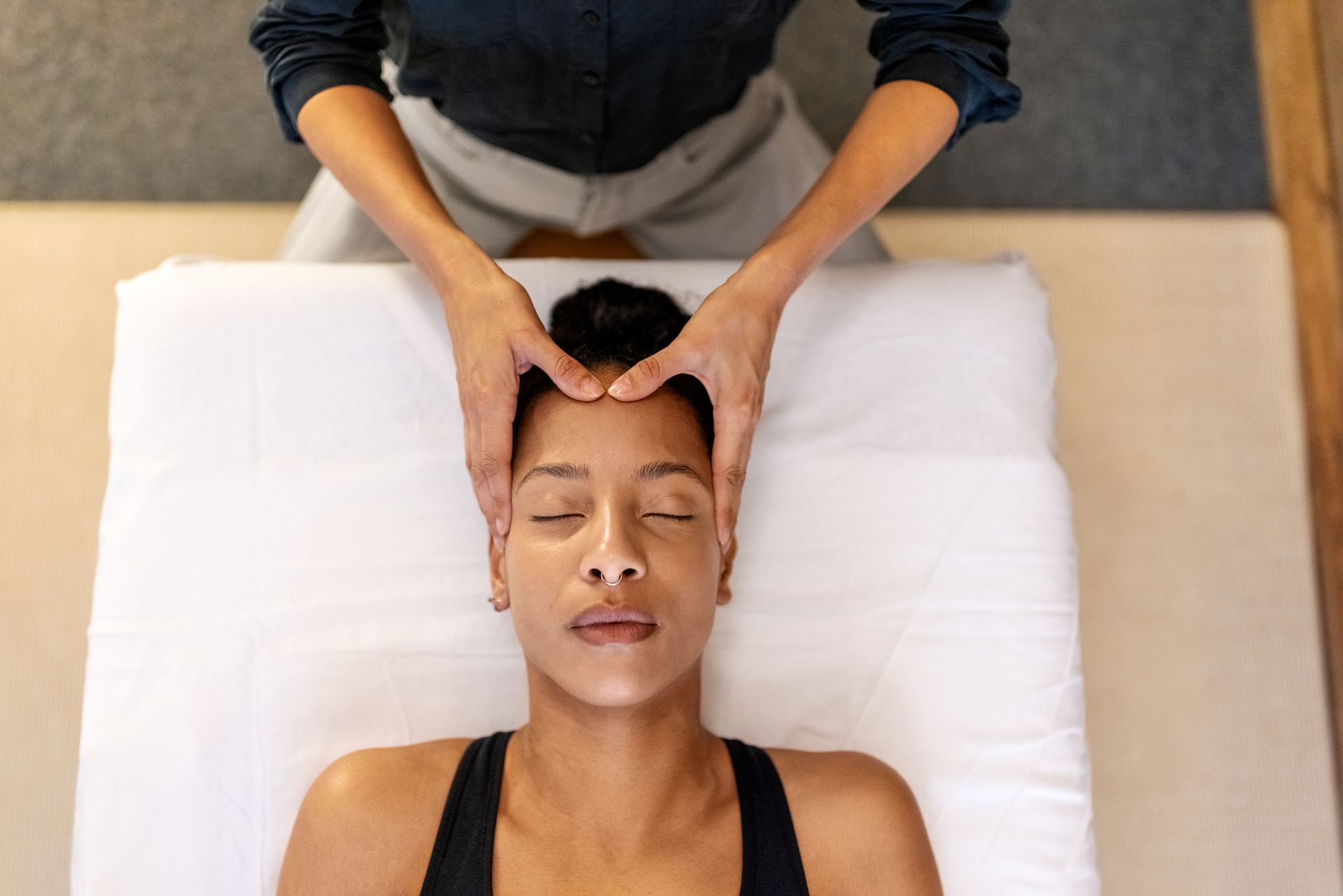Top view of a head massage done by a massage therapist to a female patient.
