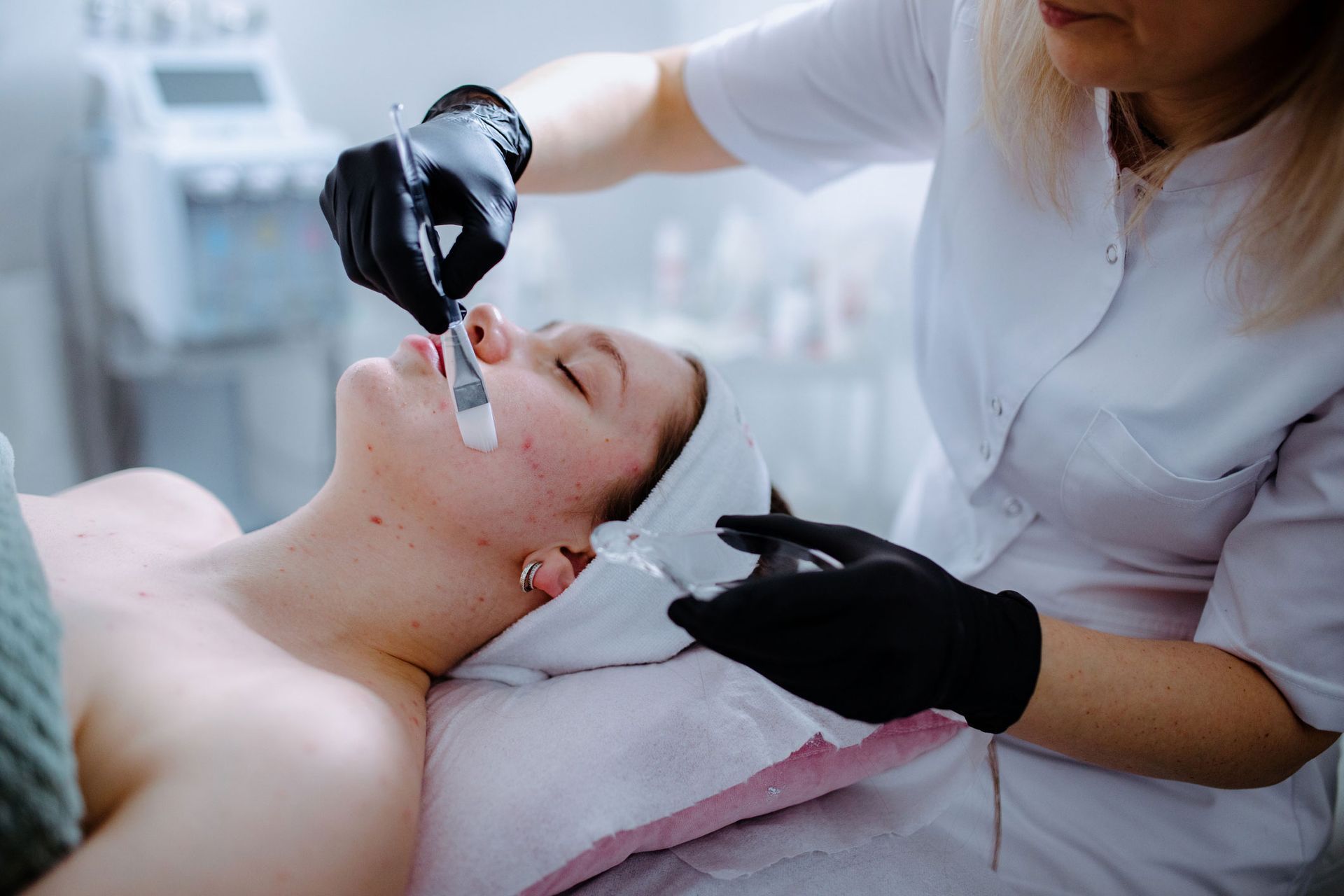 A woman receiving an acne facial treatment at a beauty salon for an improved complexion. A woman receiving an acne facial treatment at a beauty salon for an improved complexion.