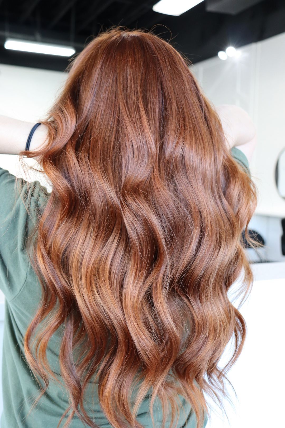 A woman with long red hair is wearing a green shirt.