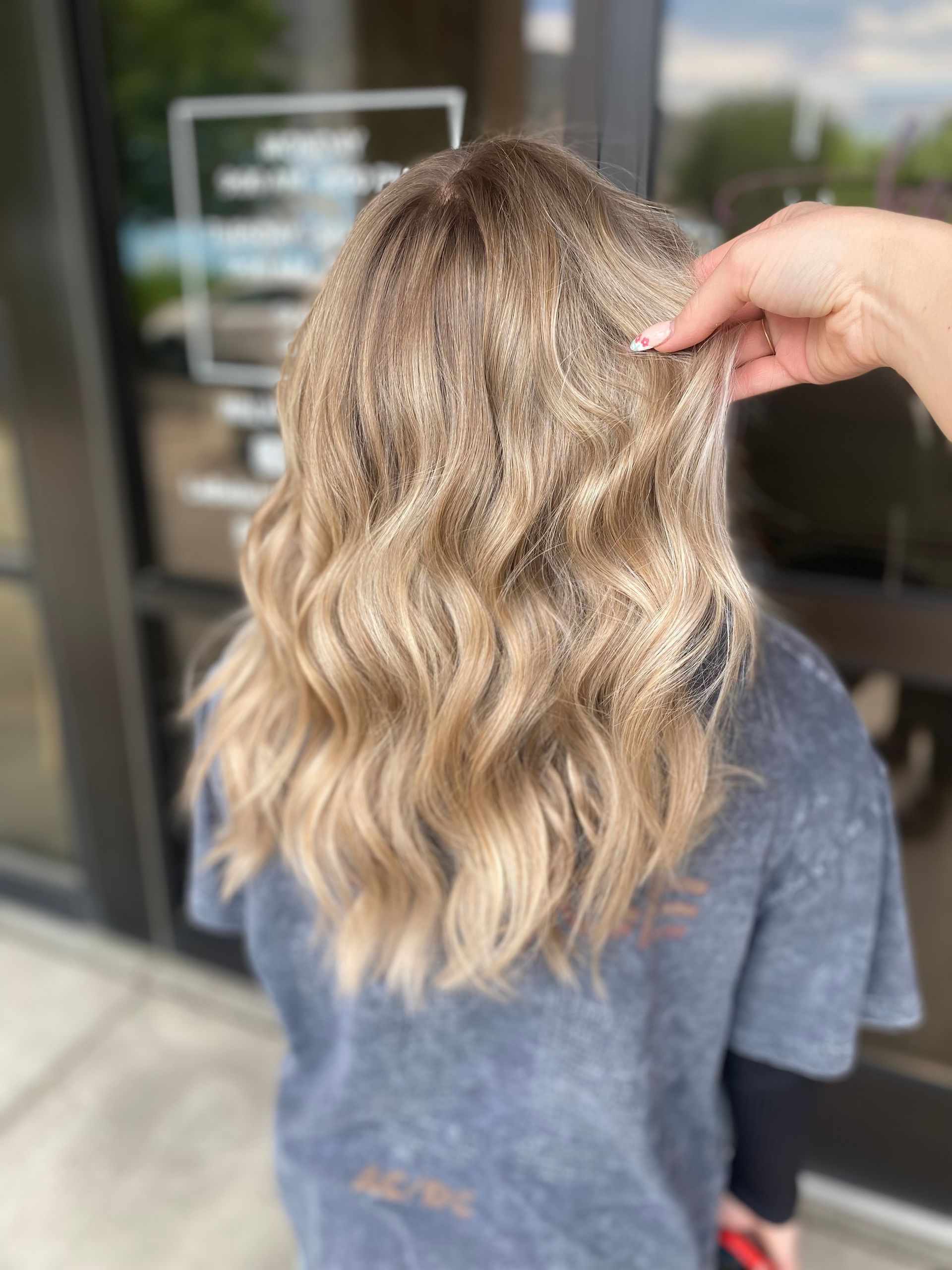 A person is touching a woman 's blonde hair in front of a building.