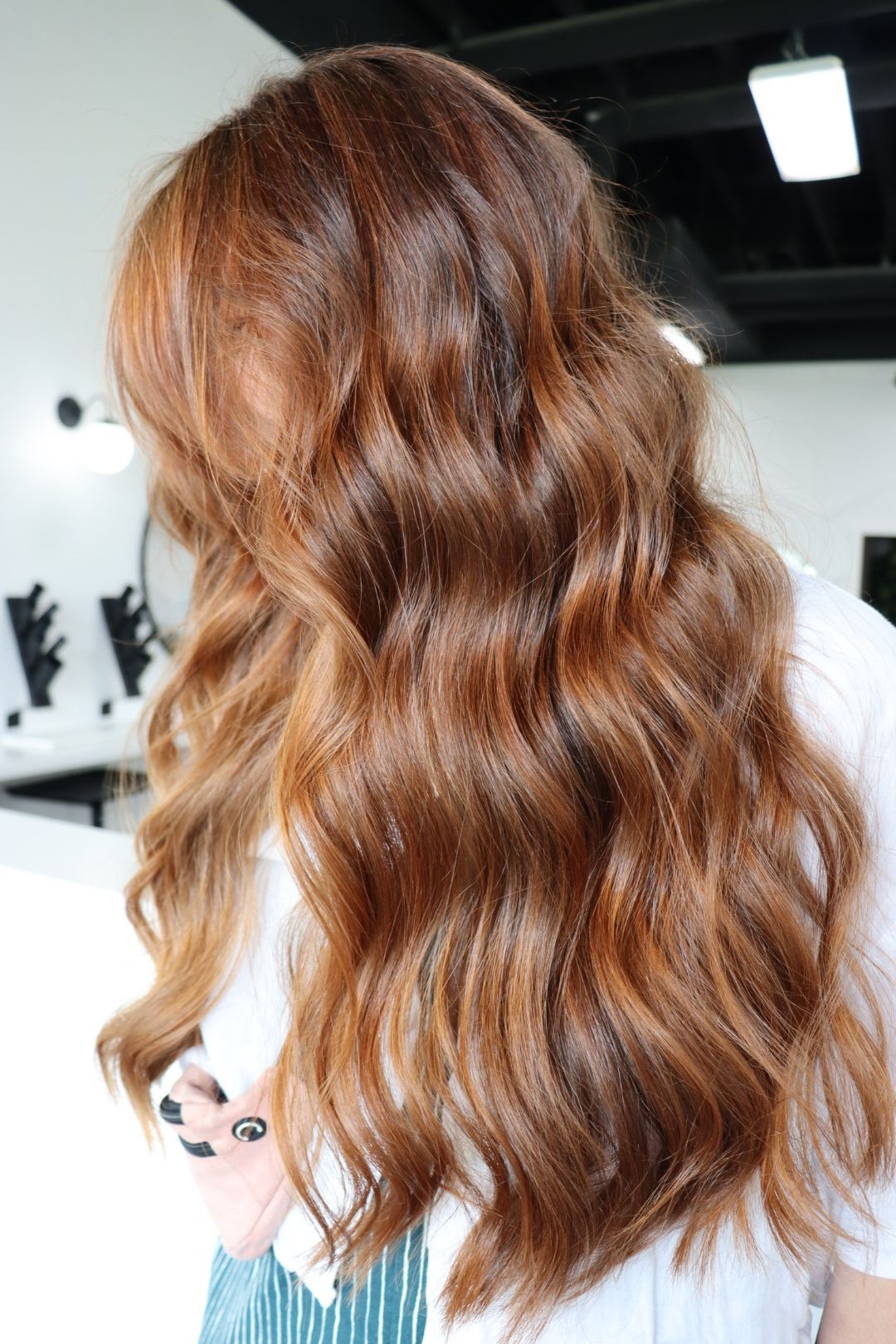 A woman with long brown hair is standing in a salon.