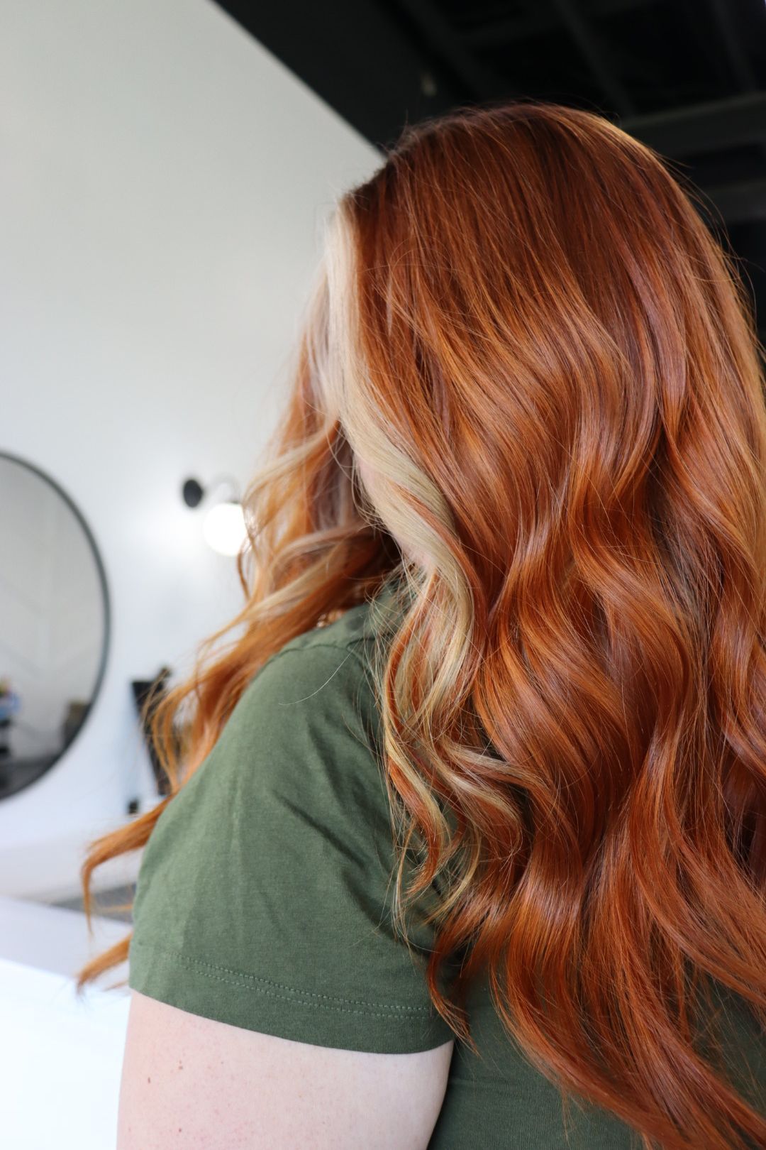 A woman with long red hair is wearing a green shirt.