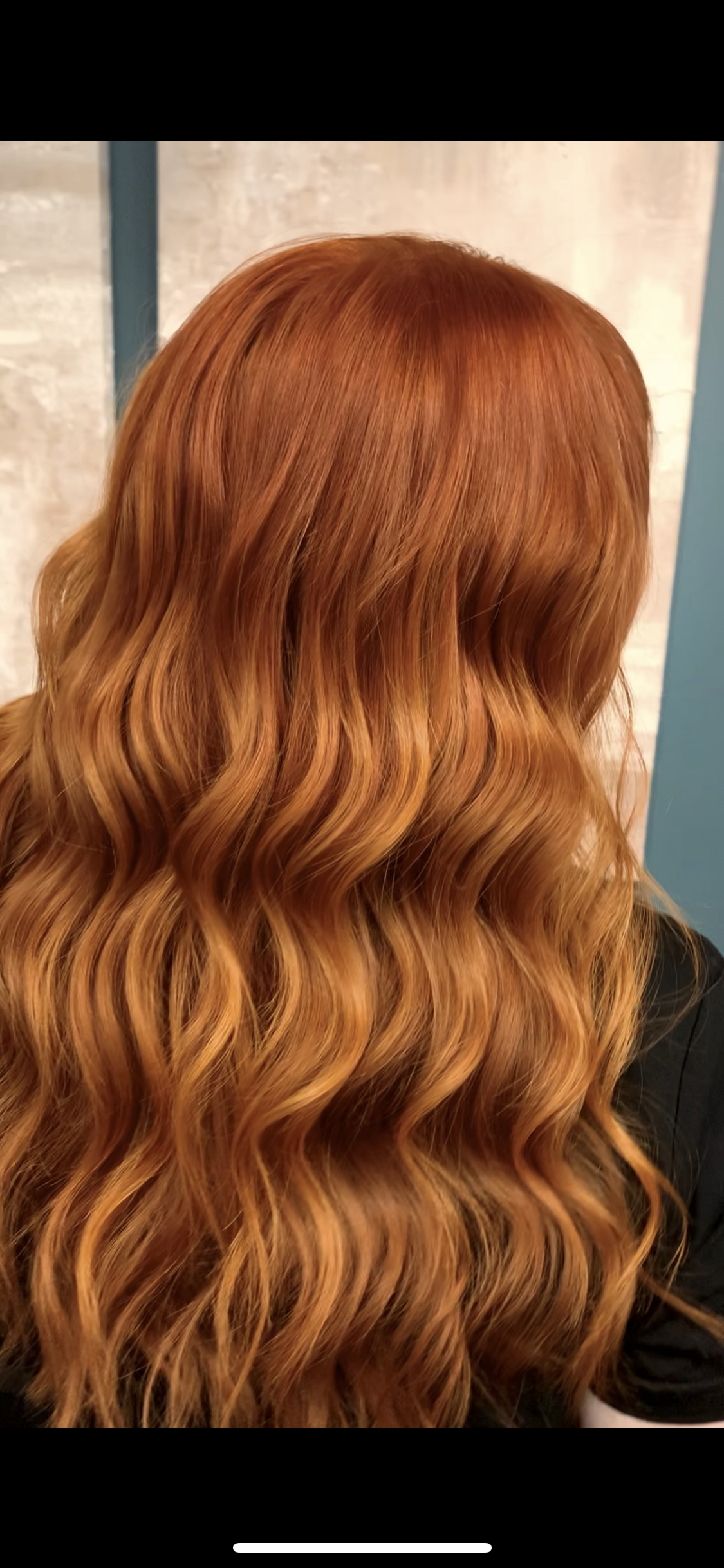 A close up of a woman 's red hair with waves.