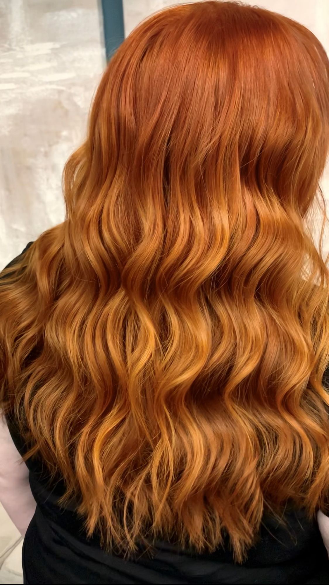 A woman with long red hair is wearing a black shirt.