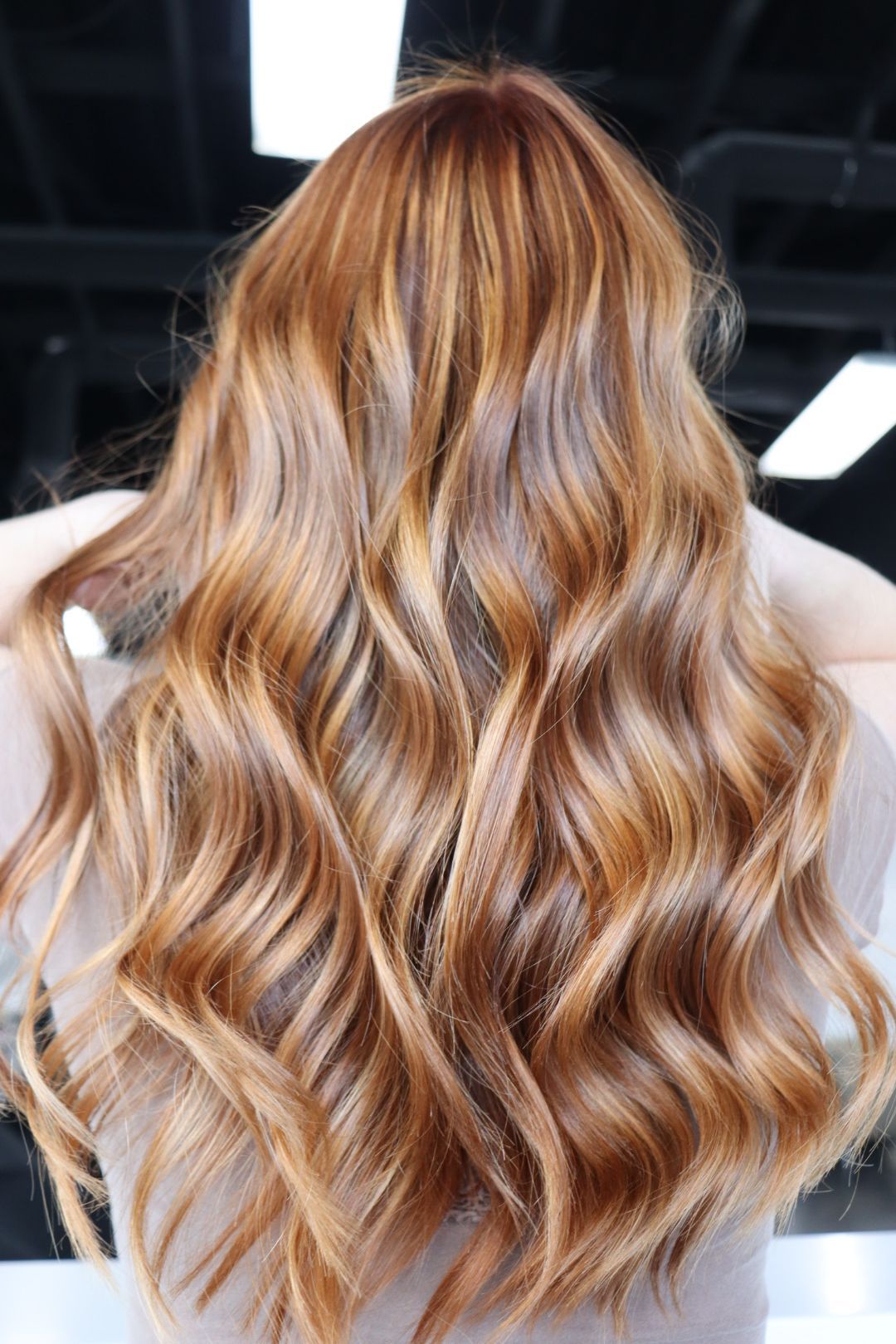 The back of a woman 's head with long wavy red hair.