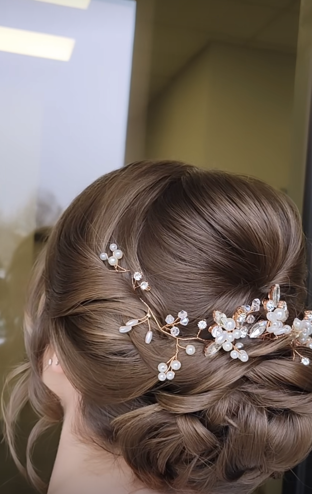 A woman is wearing a bun with pearls and flowers in her hair.