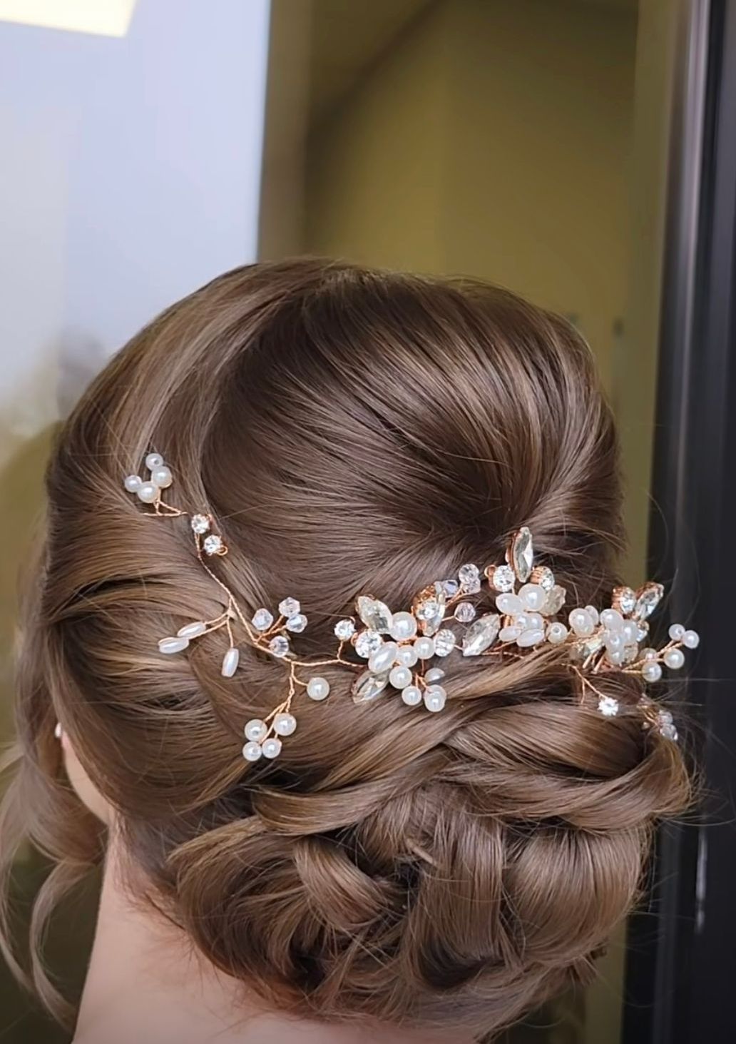 A woman is wearing a bun with a hairpiece in her hair.