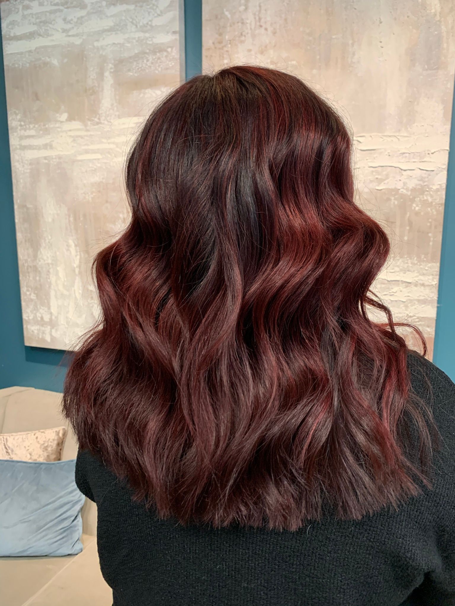 A woman with red hair is sitting on a couch in a living room.