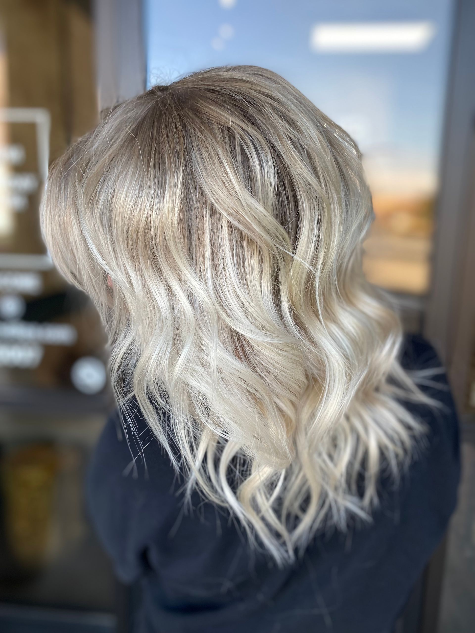 A woman with blonde hair is standing in front of a window.