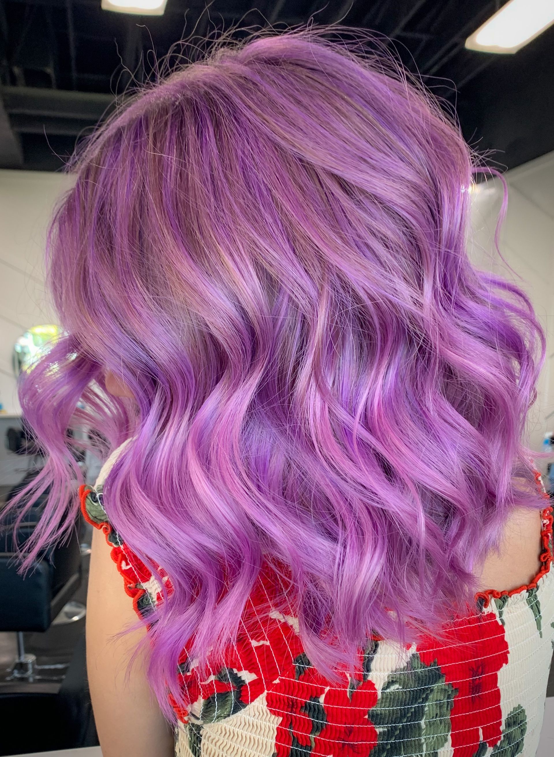 A woman with purple hair is wearing a red dress.