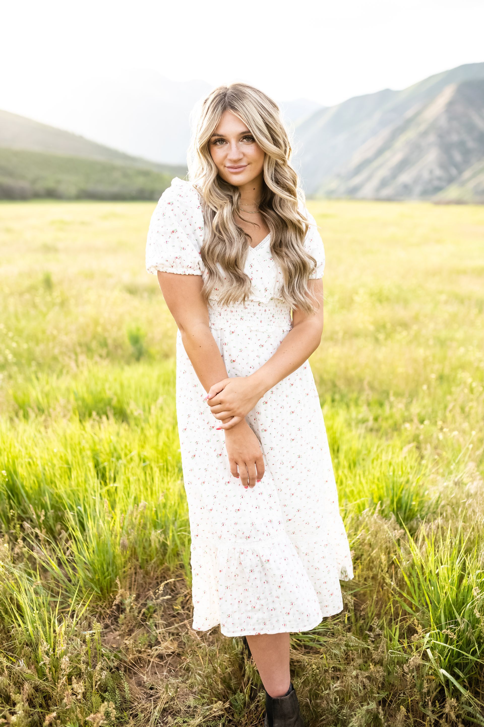 A woman in a white dress is standing in a field.
