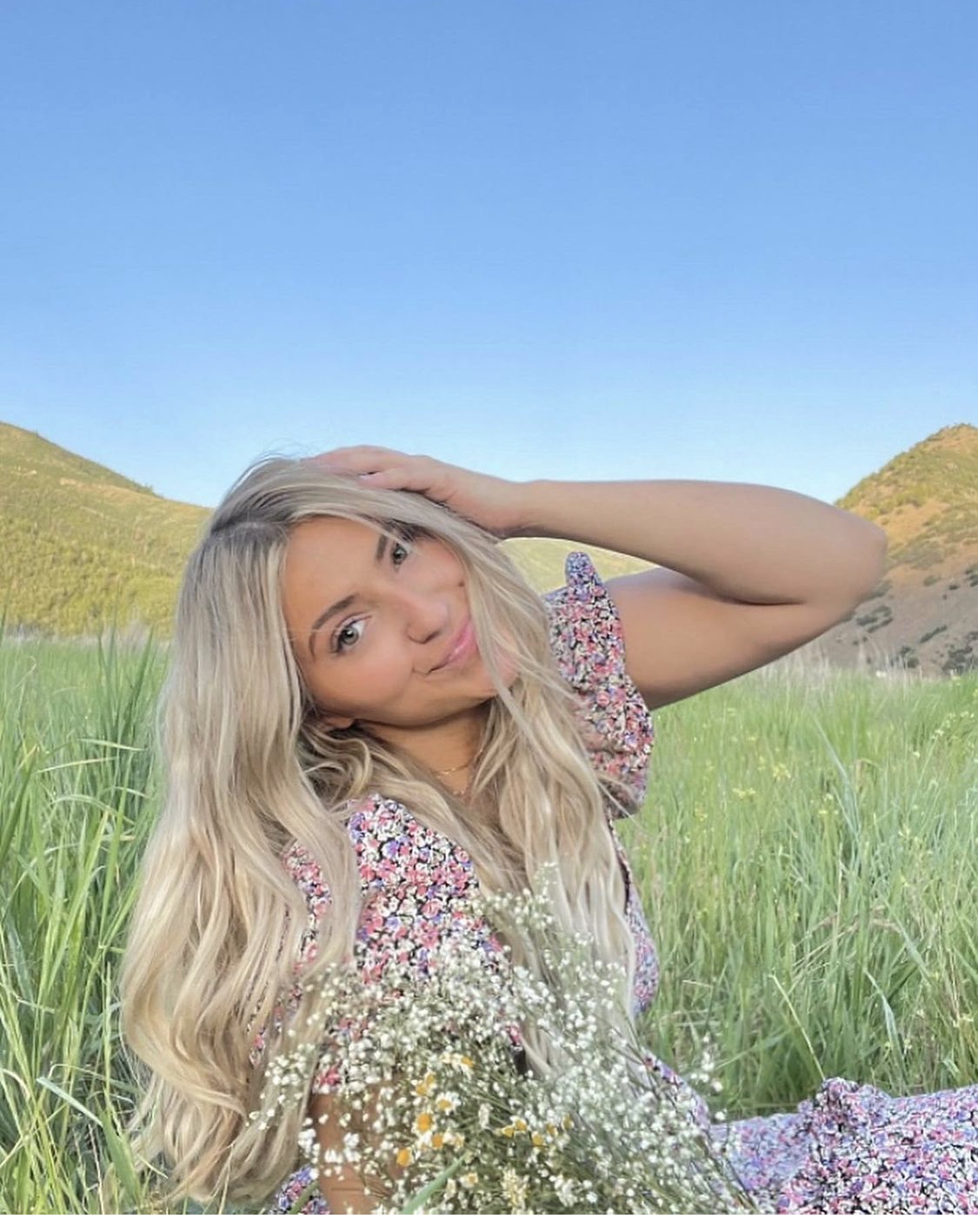 A woman in a purple dress is holding a bouquet of baby 's breath in a field.