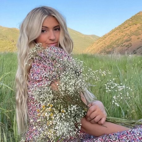 A woman in a floral dress is holding a bouquet of baby 's breath flowers.
