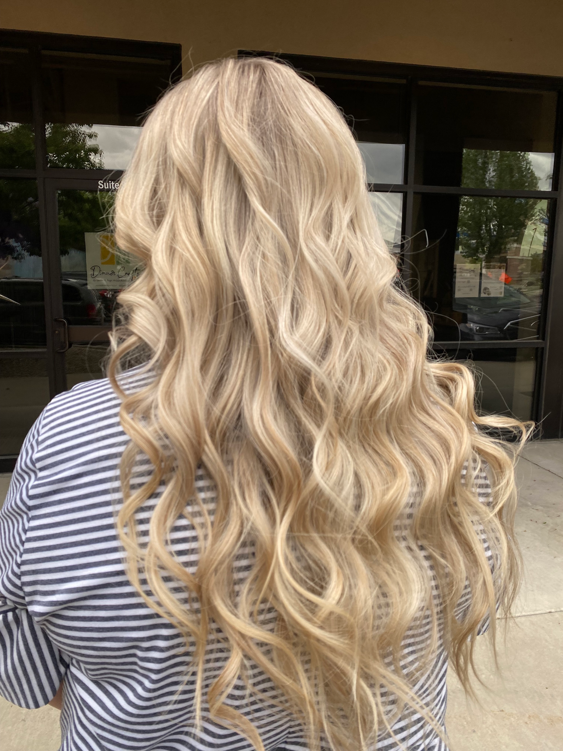 A woman with long blonde wavy hair is wearing a striped shirt.