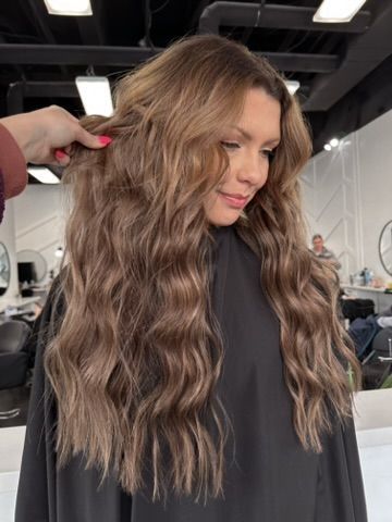 A woman is getting her hair cut at a salon.