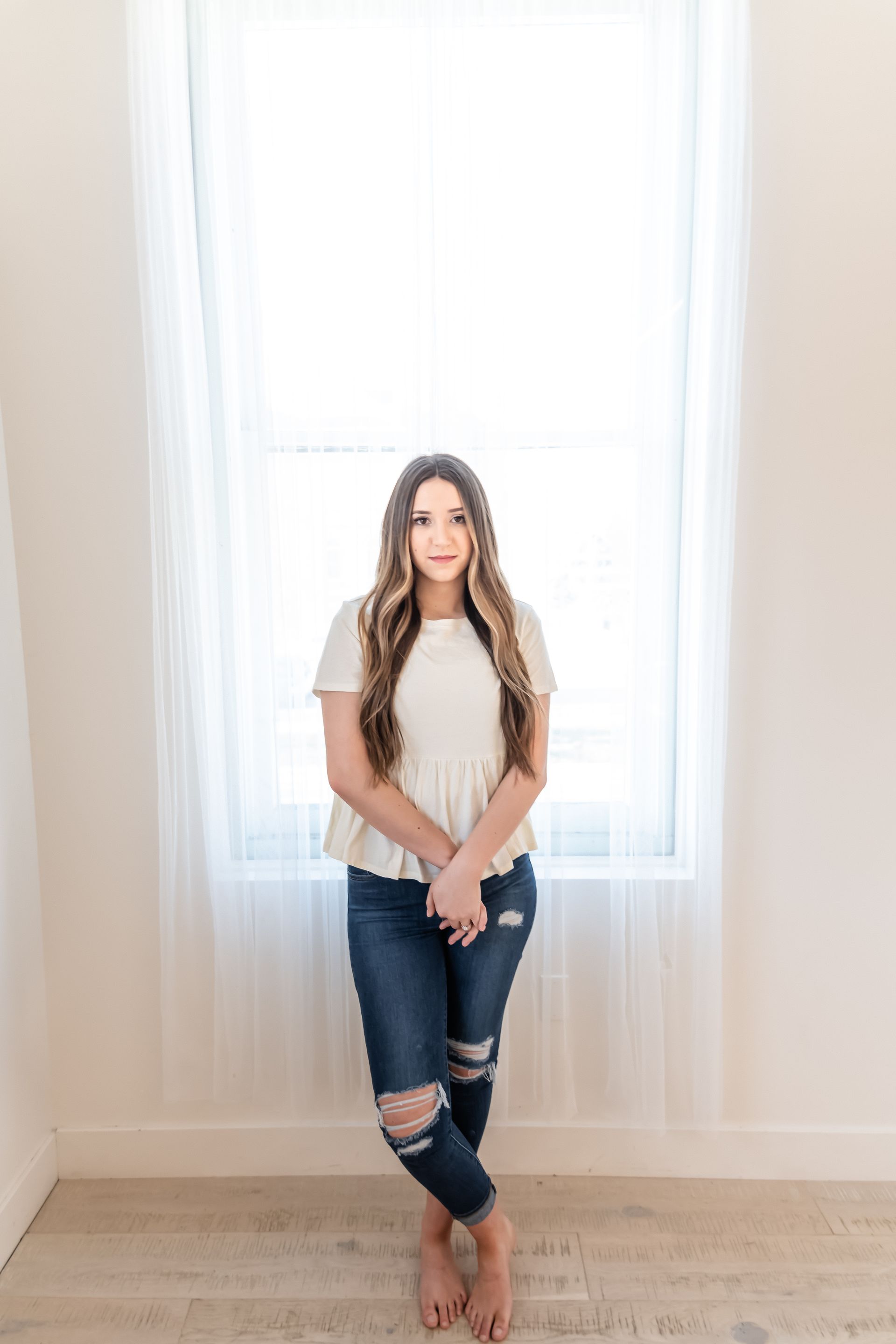 A woman is standing in front of a window in a room.
