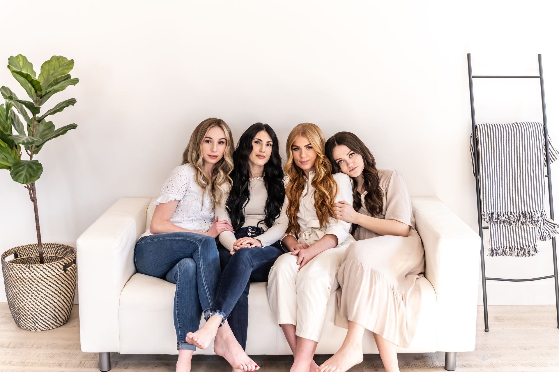 A group of women are sitting on a white couch.
