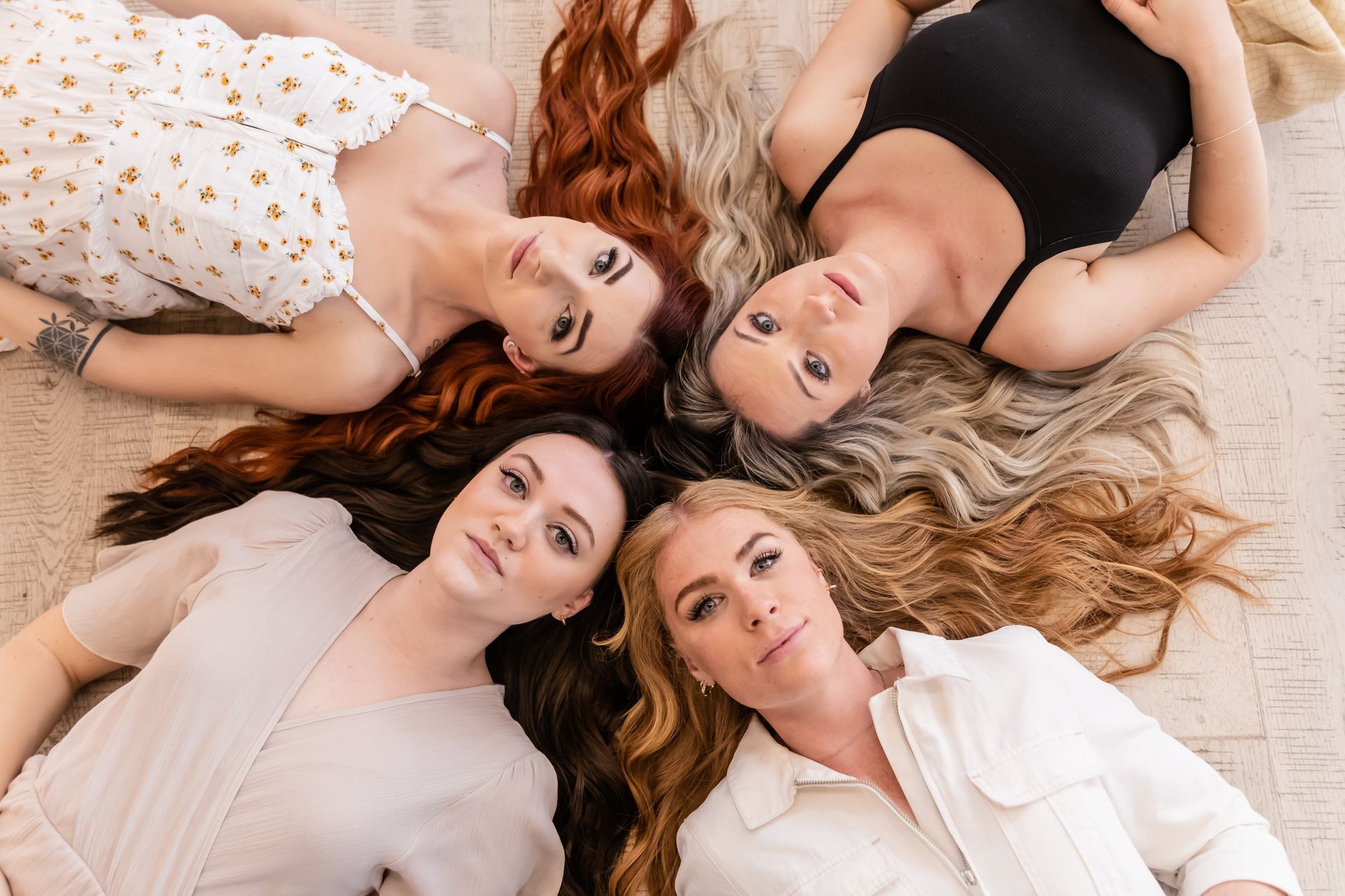 Four women are laying on the floor in a circle with their hair in a circle.
