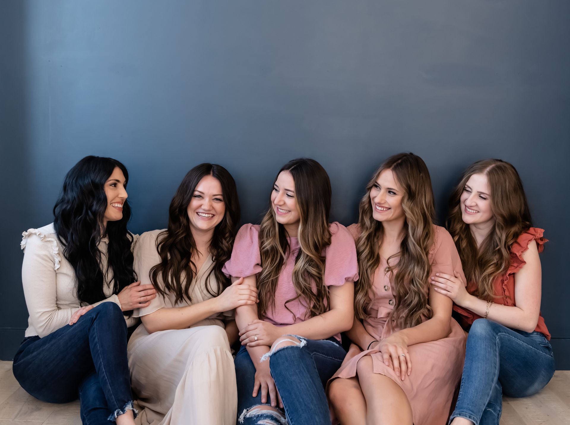 A group of women are sitting next to each other on the floor.