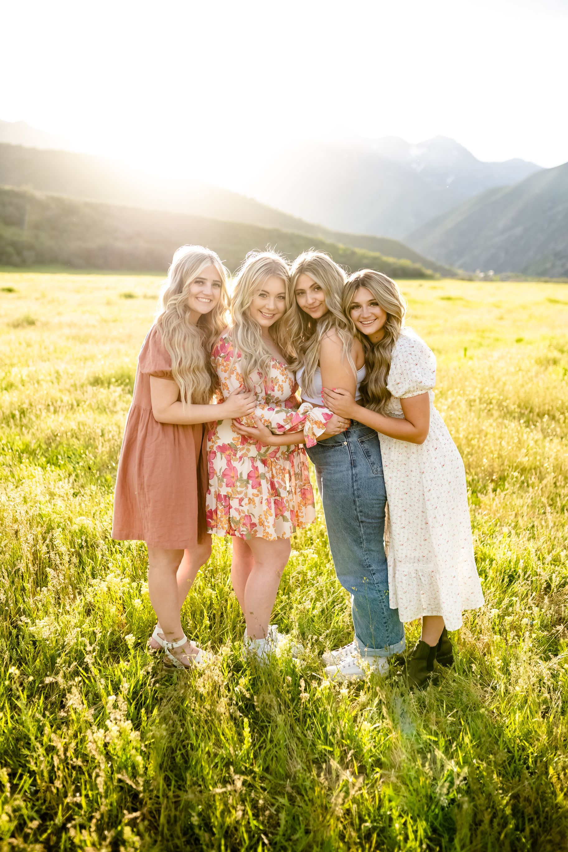 Three women are standing in a field hugging each other.