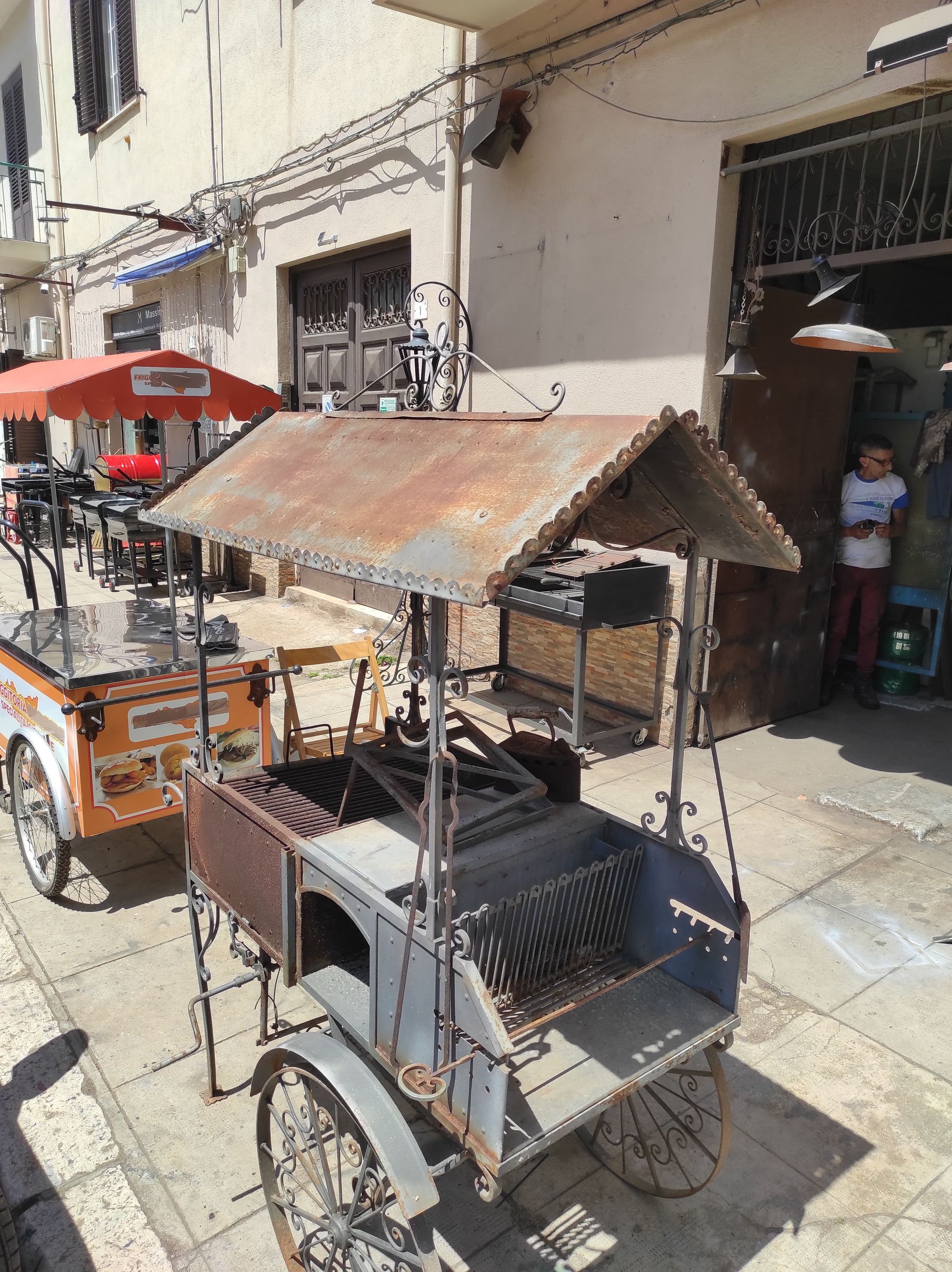 Carretti dei venditori ambulanti con tetti di metallo arrugginito in una strada soleggiata. Persona sullo sfondo.